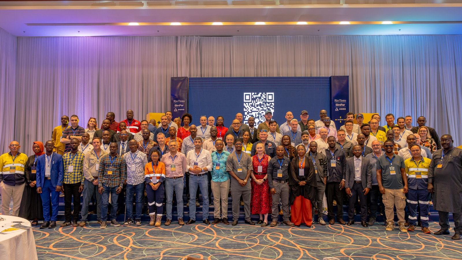 Photo de groupe des participants au forum sur la sécurité Rio Tinto SimFer, réunis devant un fond aux couleurs du projet Simandou à Conakry.